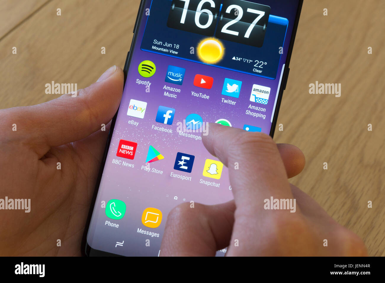 Una giovane donna selezionando il Facebook Messenger app su uno smartphone Foto Stock