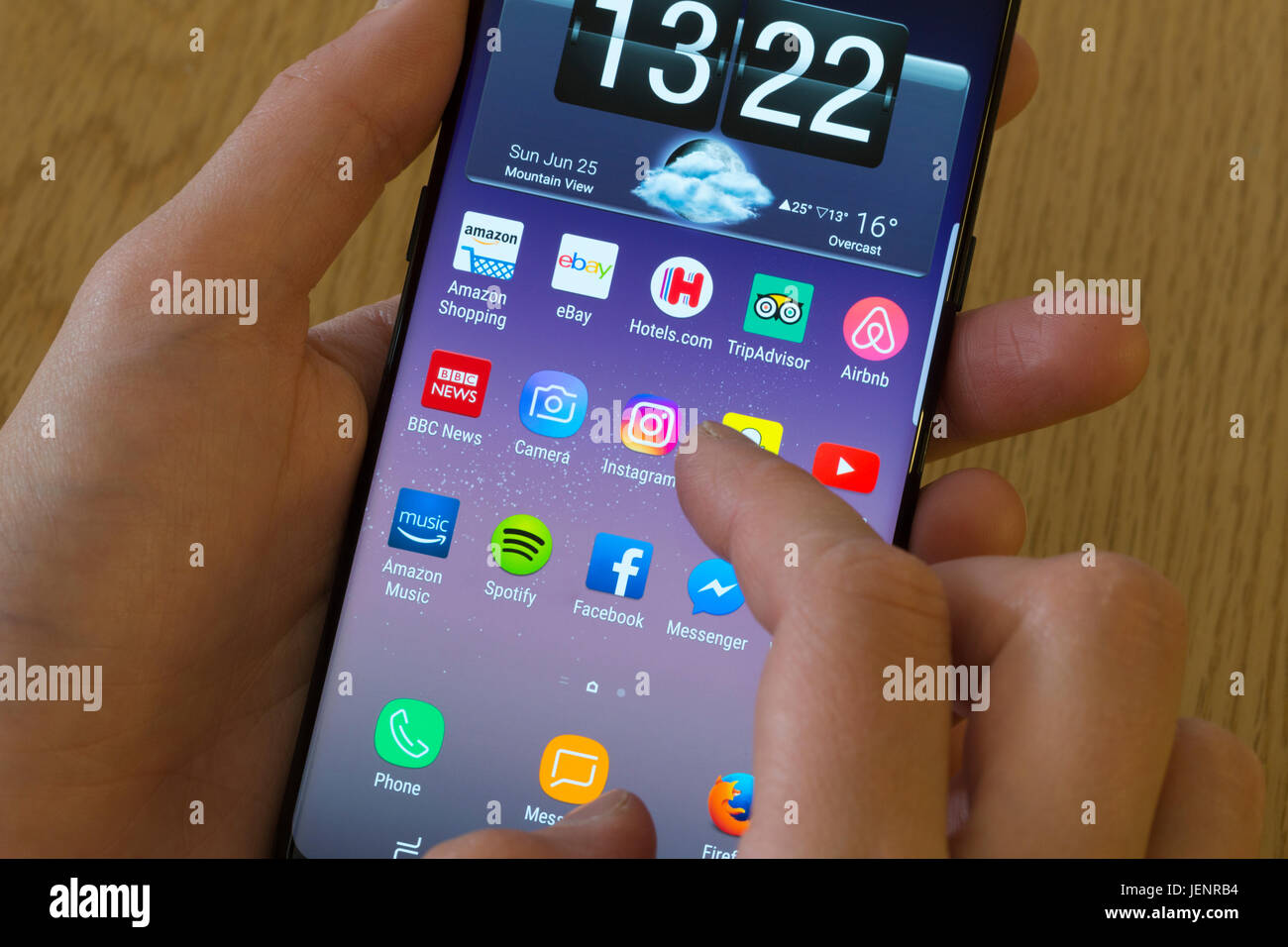 Una giovane donna selezionando il Instagram app su uno smartphone Foto Stock