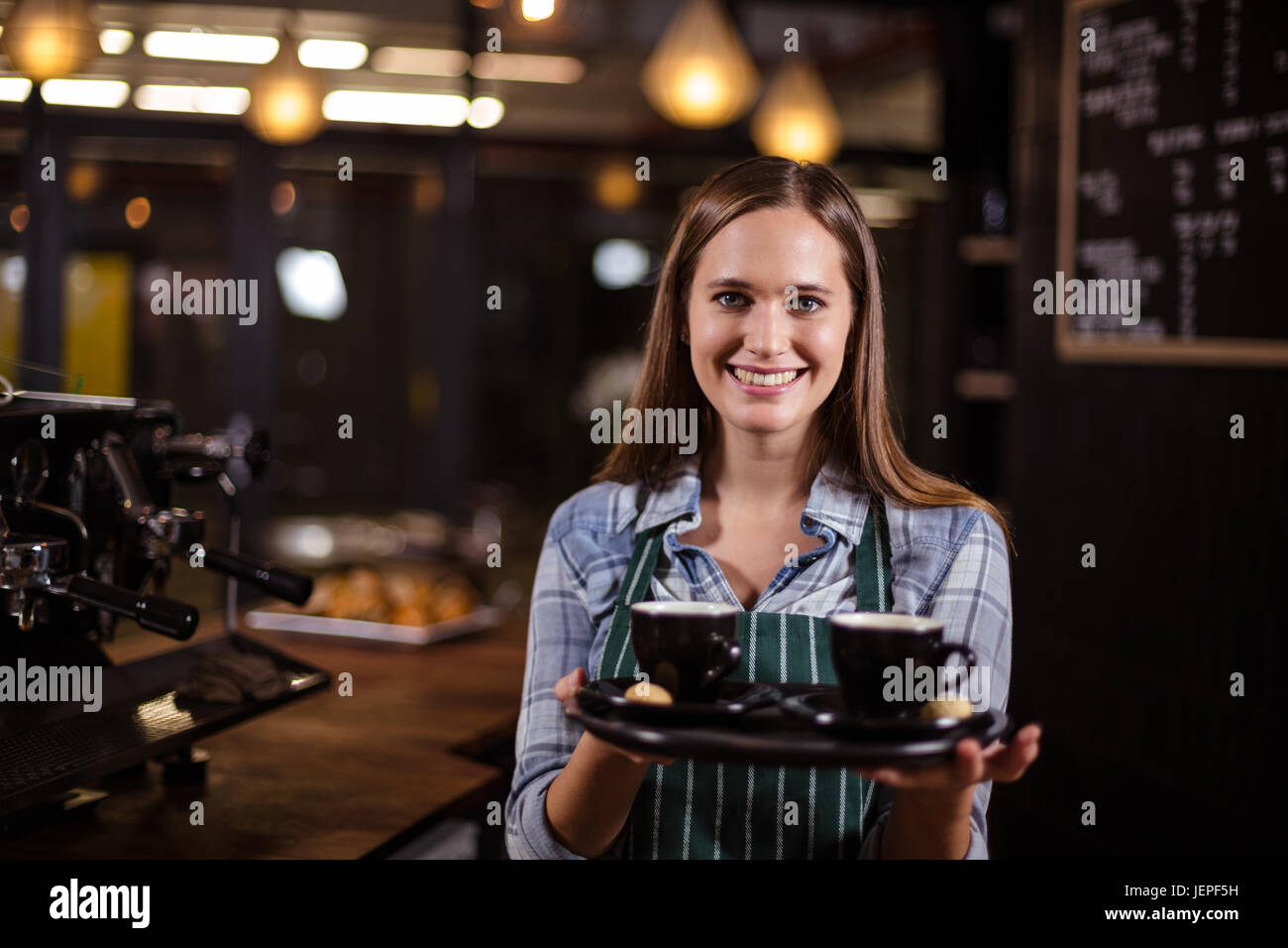 Sorridente barista tenendo il vassoio con i caffè Foto Stock