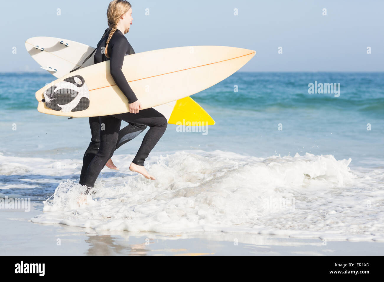 Donna con la tavola da surf a correre verso il mare Foto Stock