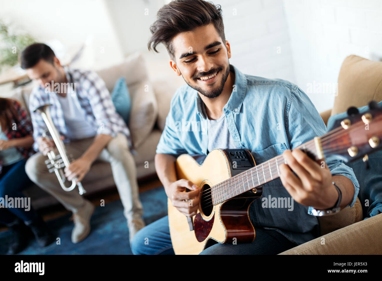 Giovane uomo bello suonare la chitarra per i suoi amici Foto Stock