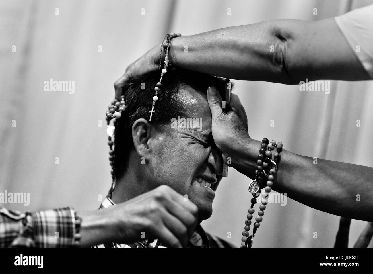 Un colombiano pastore, premendo il crocifisso su un credente la testa, tenta di sfrattare un presunto demone durante il rituale di esorcismo eseguito ad una Chiesa casa a Bogotà, Colombia, 10 marzo 2016. Centinaia di cristiani belivers, riunite in gruppi anonimi, raccogliere ev | Utilizzo di tutto il mondo Foto Stock