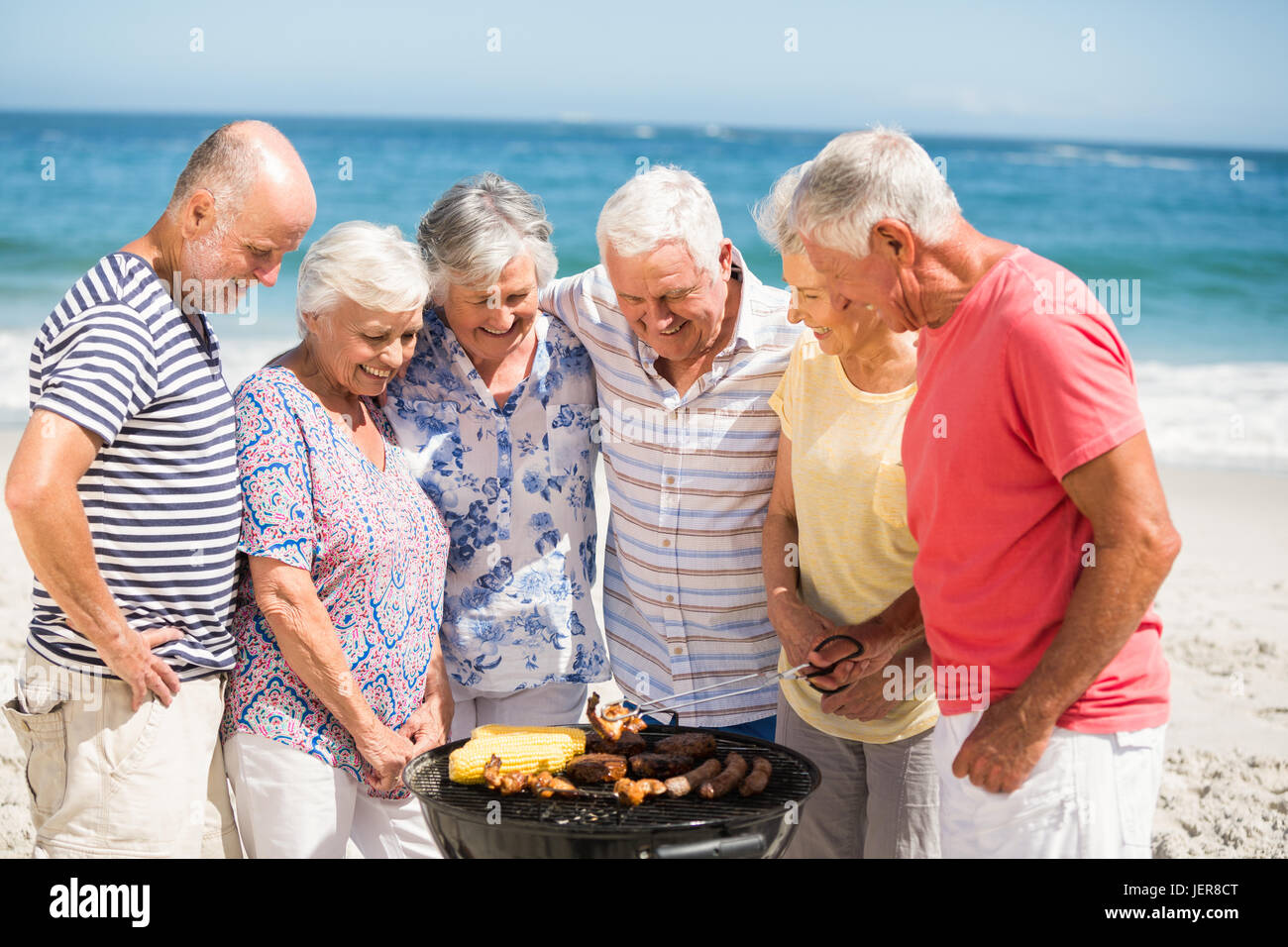 Senior avente un barbecue sulla spiaggia Foto Stock