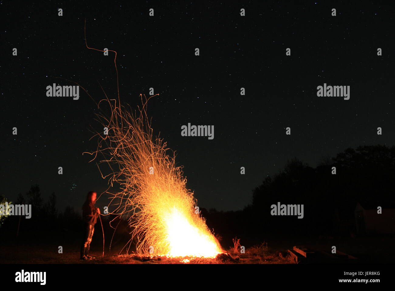 Persona sfocate, chiara fiamma. Wild scintille volare liberamente attraverso il buio dell'aria. Il calore è ancora di fronte a noi, ma il meglio deve ancora venire. Foto Stock