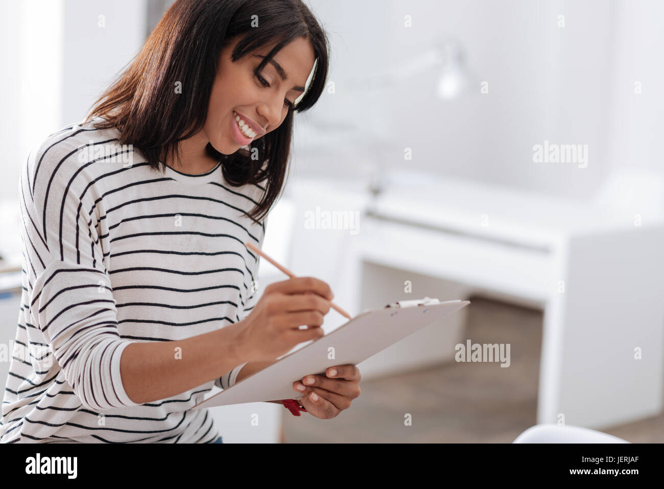 Felice donna piacevole scrivere nei suoi appunti Foto Stock