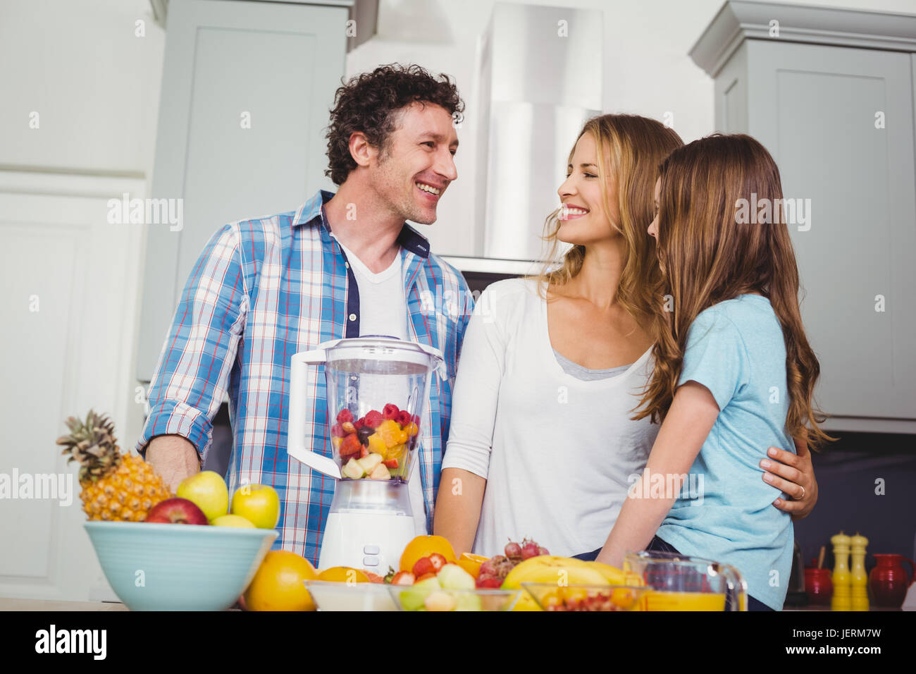 La famiglia felice la preparazione di succhi di frutta a tavola Foto Stock