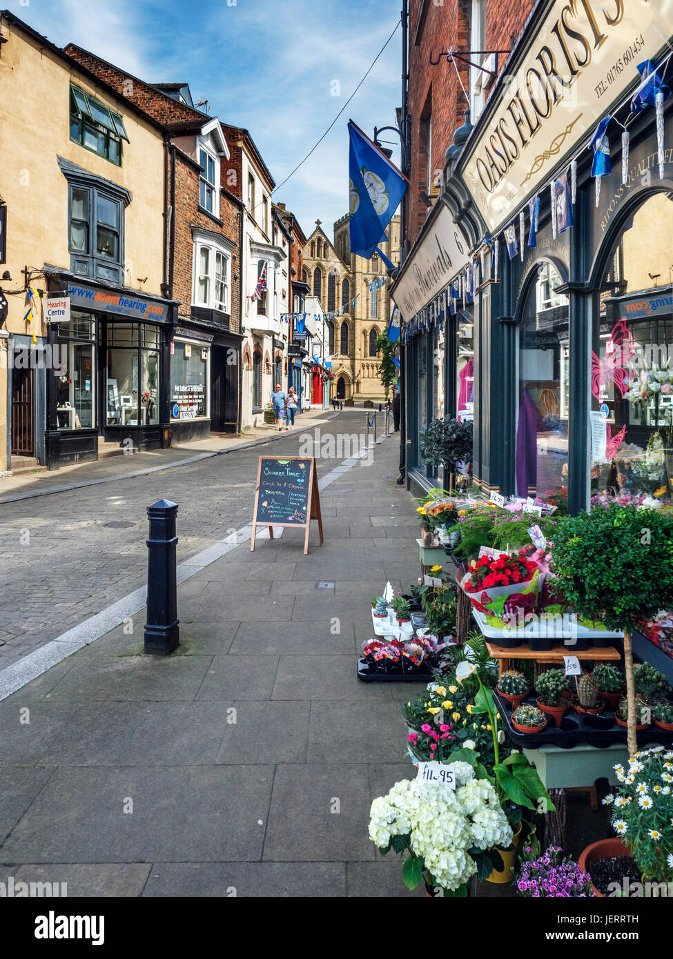 Fioraio e negozi a Kirkgate in Ripon con la cattedrale In lontananza North Yorkshire Inghilterra Foto Stock