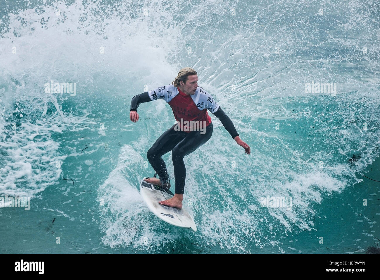 Navigare in UK. Navigare in Cornovaglia. Spettacolare azione di surf come un surfista cavalca un onda in un concorso a Fistral Beach in Newquay. Foto Stock