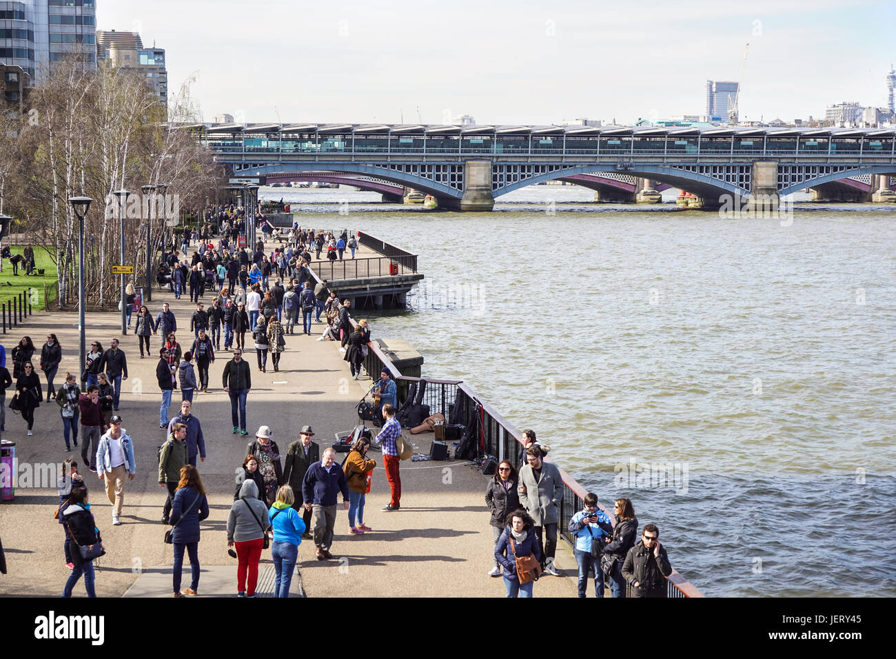 LONDON, Regno Unito - 6 April 2017: turisti passeggiata alberata percorso sulla sponda sud del fiume Tamigi su una soleggiata giornata di primavera Foto Stock