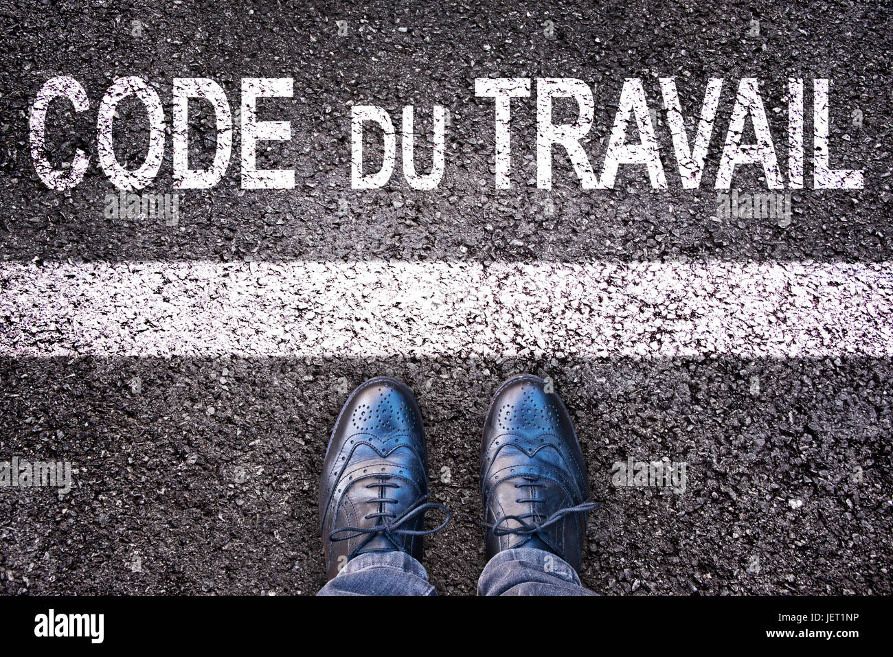 Code du travail (significato del codice del lavoro francese) scritto su una strada asfaltata sfondo con gambe Foto Stock