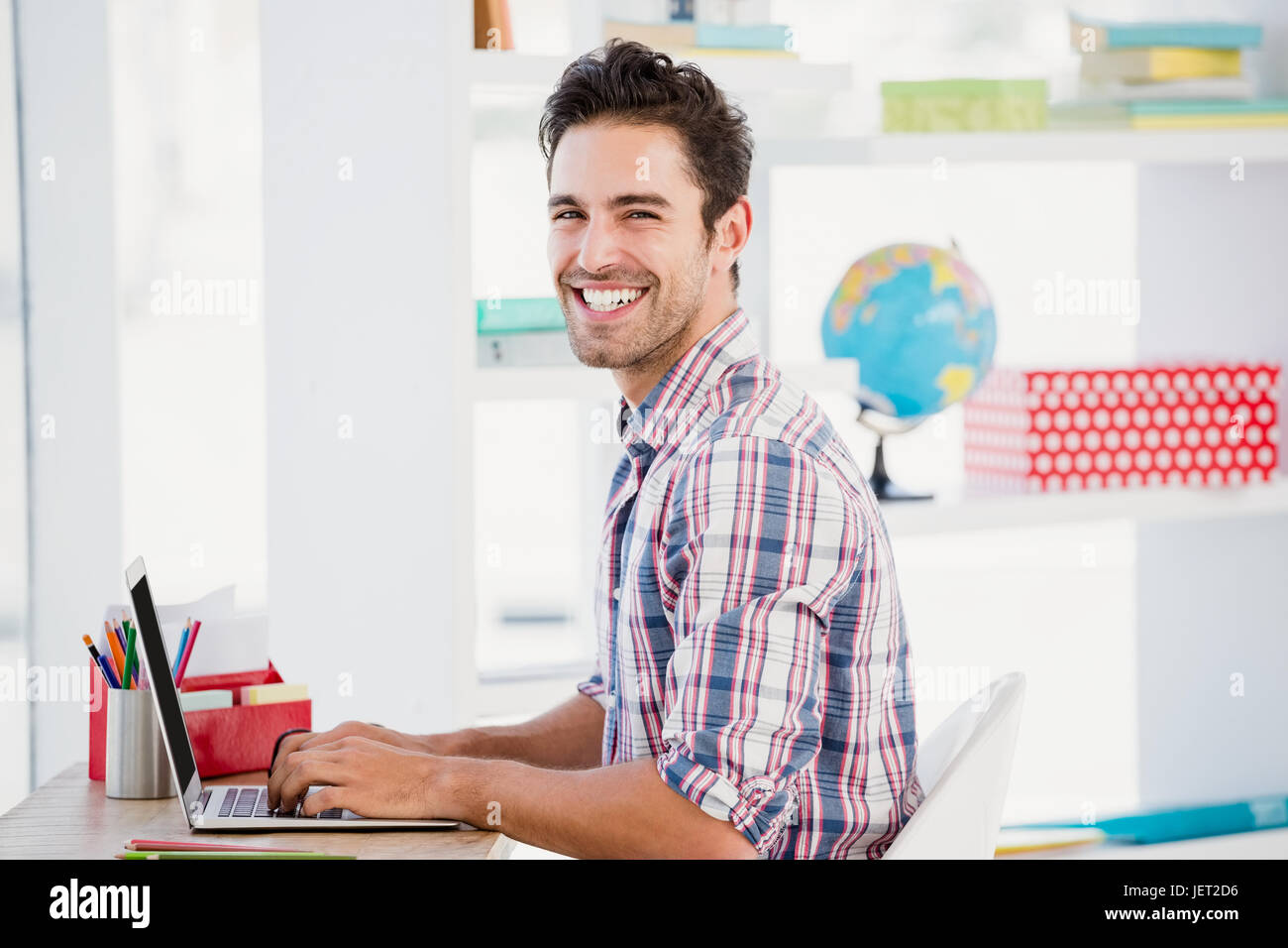Giovane uomo utilizzando computer portatile presso la sua scrivania Foto Stock