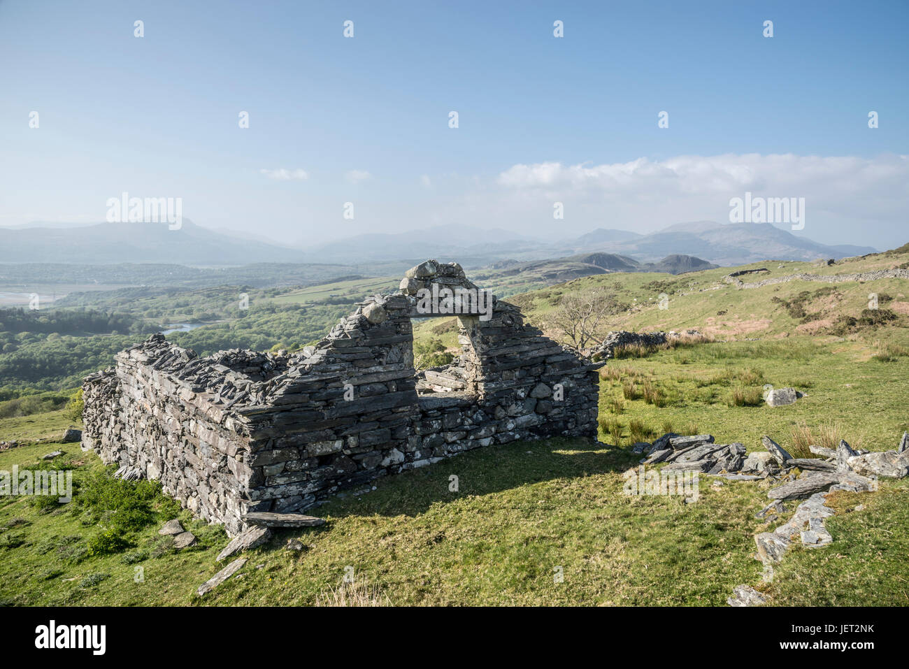 Antica fattoria in pietra in costruzione sulle colline vicino a Harlech in Snowdonia, il Galles del Nord. Vista spettacolare delle montagne su un luminoso pomeriggio. Foto Stock