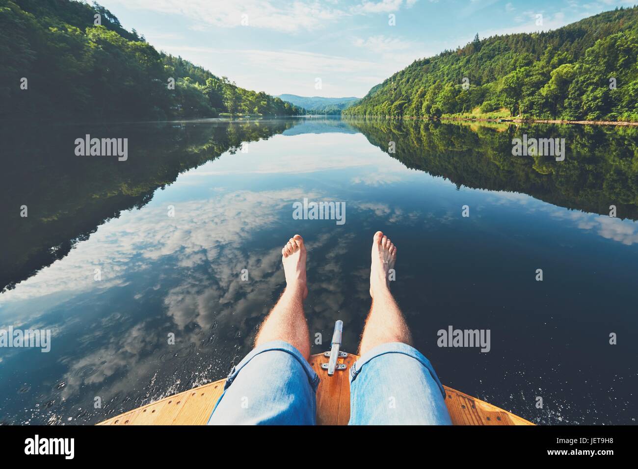 Estate relax sul fiume. Le gambe di un uomo seduto sulla prua della barca. Il fiume Moldava vicino a Praga, Repubblica Ceca Foto Stock