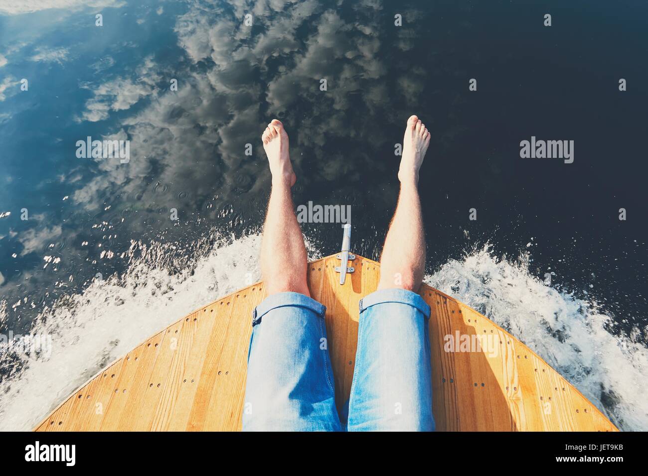 Estate relax sul fiume. Le gambe di un uomo seduto sulla prua della barca. Foto Stock