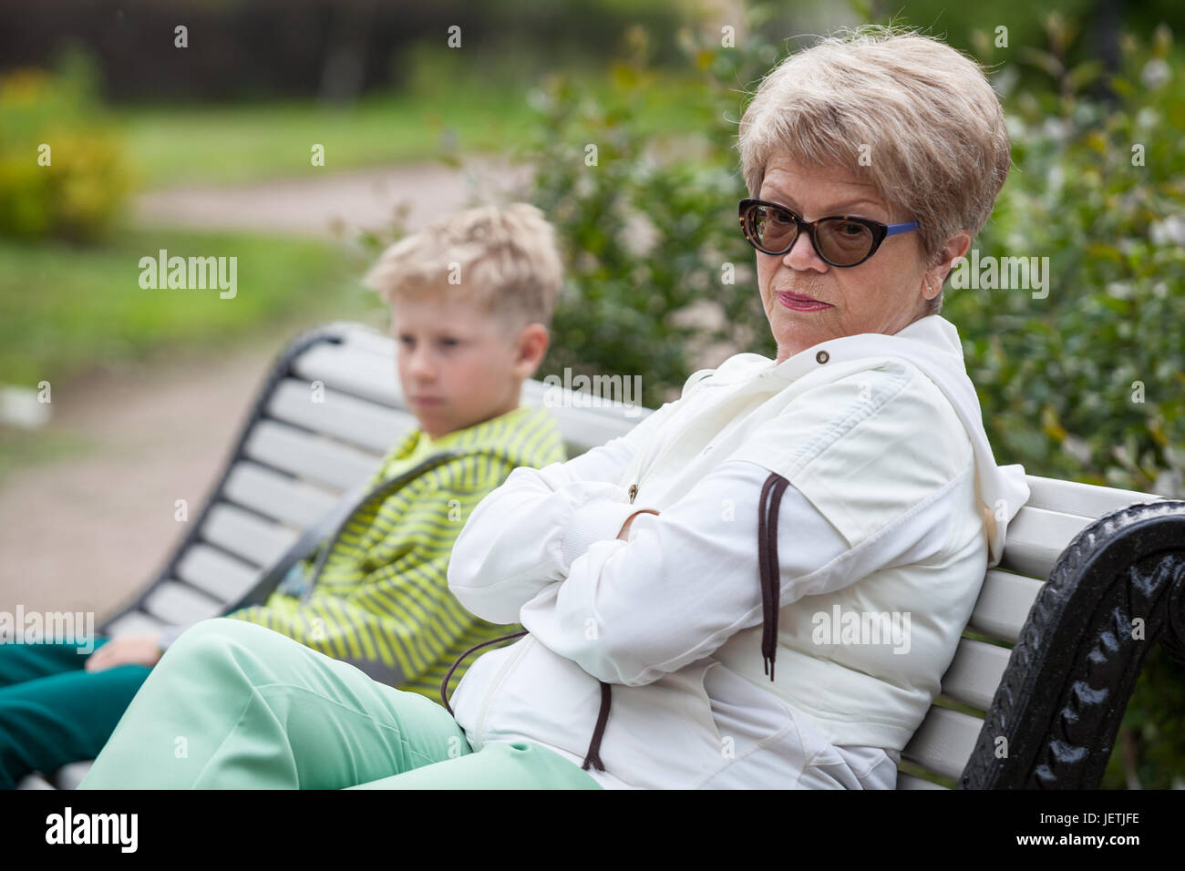 Nonna europea e nipote di conflitto, due persone sedute in chiuso pone sul banco in posizione di parcheggio Foto Stock