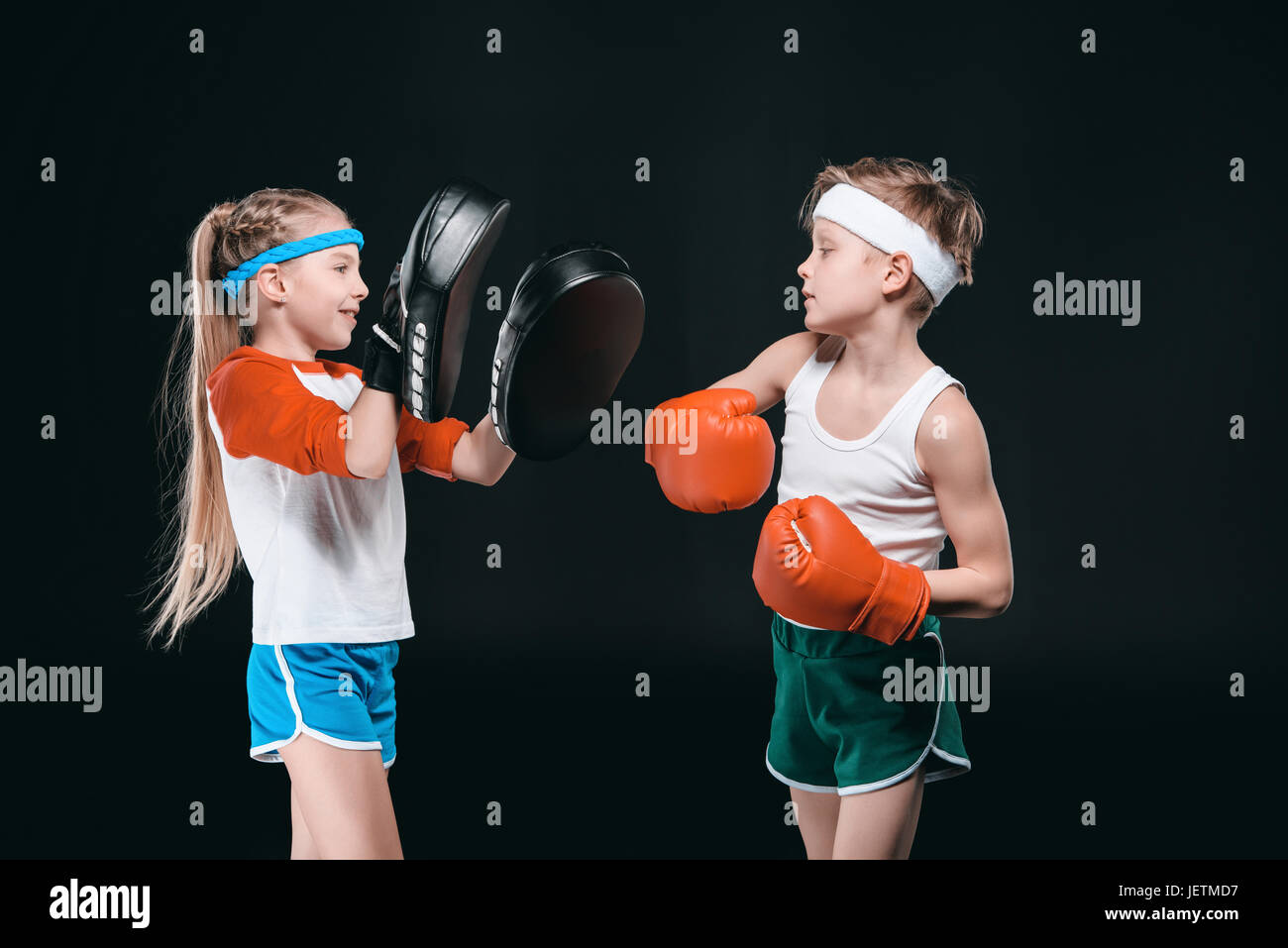 Vista laterale del ragazzo e ragazza di boxe abbigliamento sportswear isolato sul nero, attività per bambini concept Foto Stock