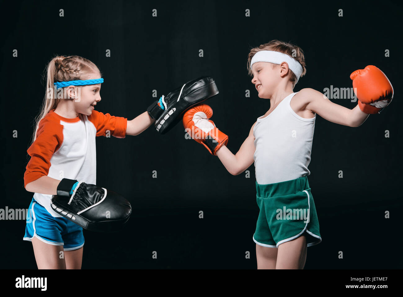 Vista laterale del ragazzo e ragazza di boxe abbigliamento sportswear isolato sul nero, attività per bambini concept Foto Stock