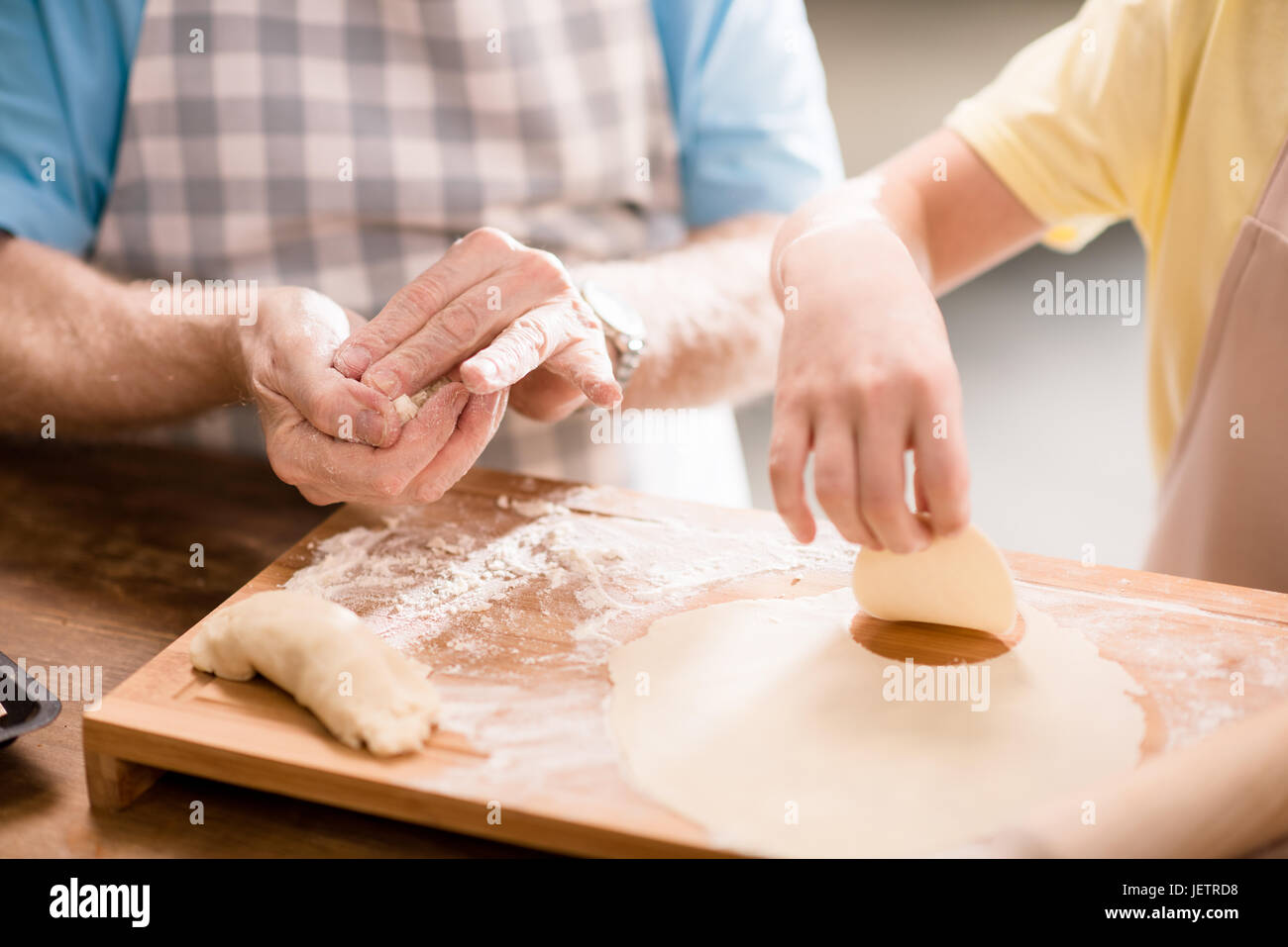 Nipote e nonno di cottura e rendendo la pasta per i biscotti con utensili da cucina al tavolo da cucina, cucina nel concetto di cucina Foto Stock