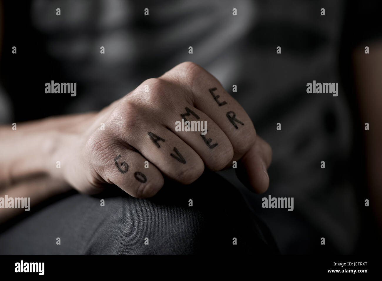 Primo piano della mano di un giovane uomo caucasico con il testo game over scritto con un inchiostro temporaneo nel suo knuckles, con un effetto drammatico Foto Stock