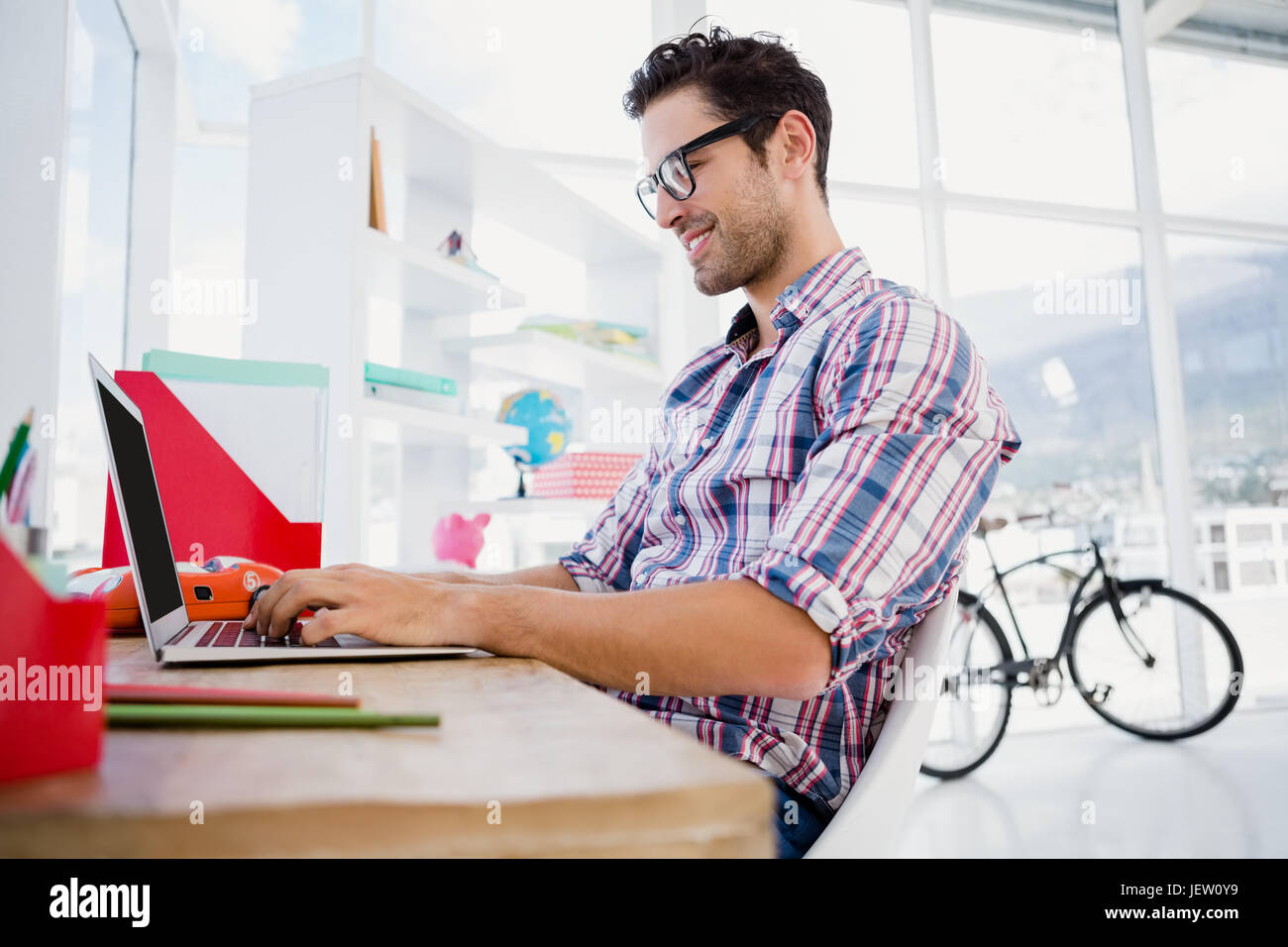 Giovane uomo che lavora alla sua scrivania Foto Stock