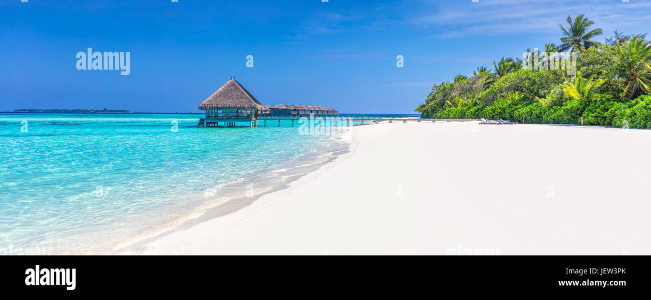 Panorama di ampia spiaggia di sabbia su un isola tropicale delle Maldive. Palme da cocco e acqua lodge sull Oceano Indiano. Foto Stock