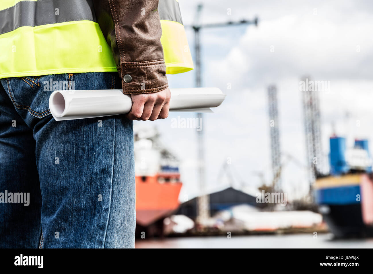 Ingegnere navale sta allo scalo in un porto. L uomo è in possesso di documenti di costruzione. Industria cantieristica navale Foto Stock