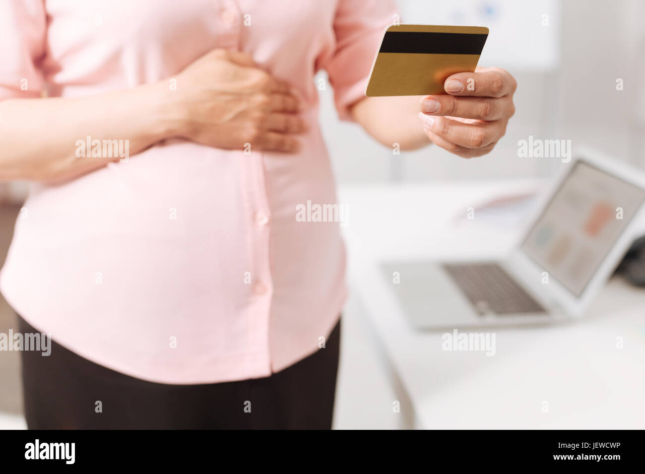 Piacevole la donna incinta in possesso di una carta di credito Foto Stock