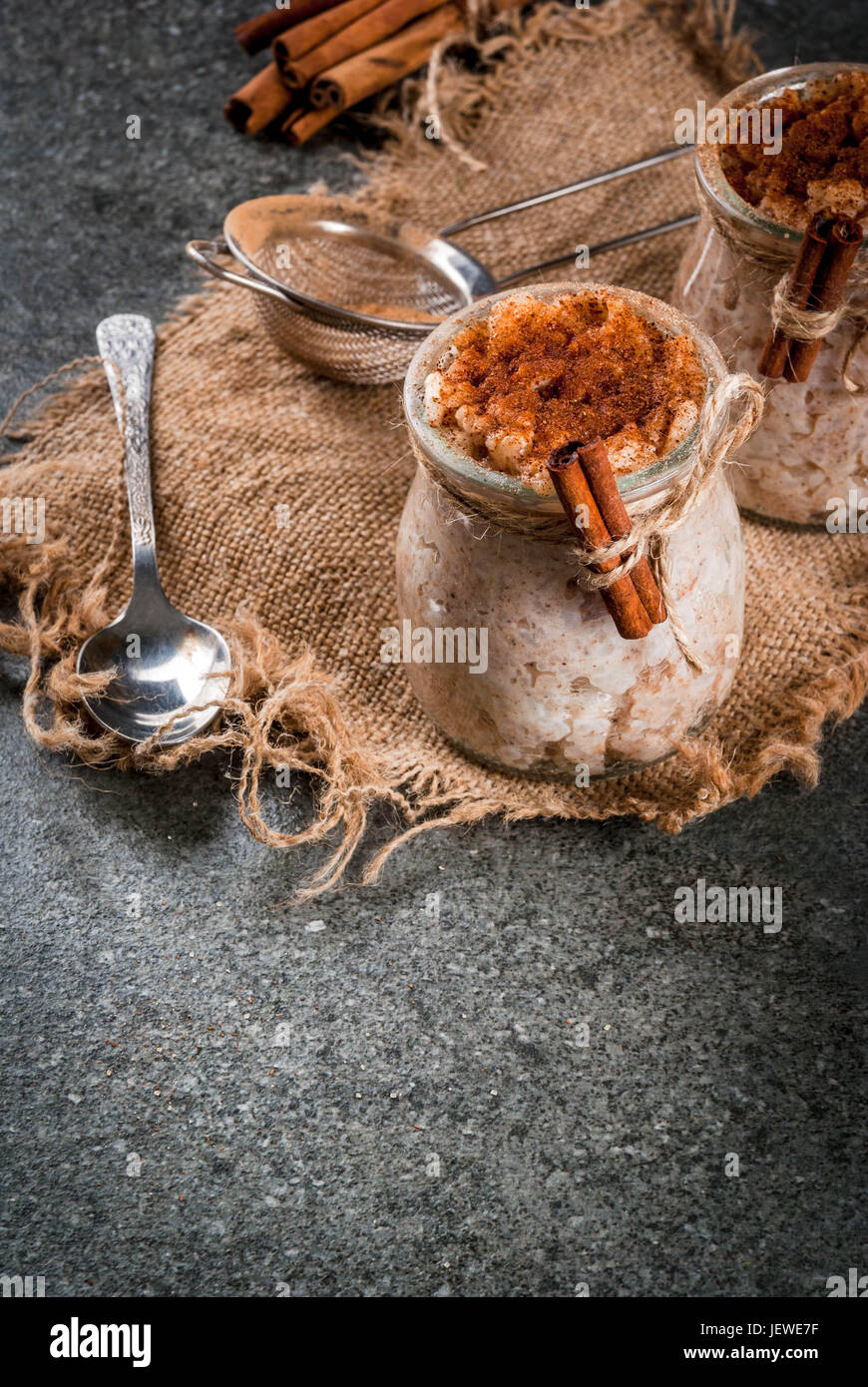 Spagnolo, Sud Americana, Messicana dessert. Sweet porridge, budino di riso. Arroz con leche. In porzionato giare, decorata con cannella e zucchero. Su un da Foto Stock