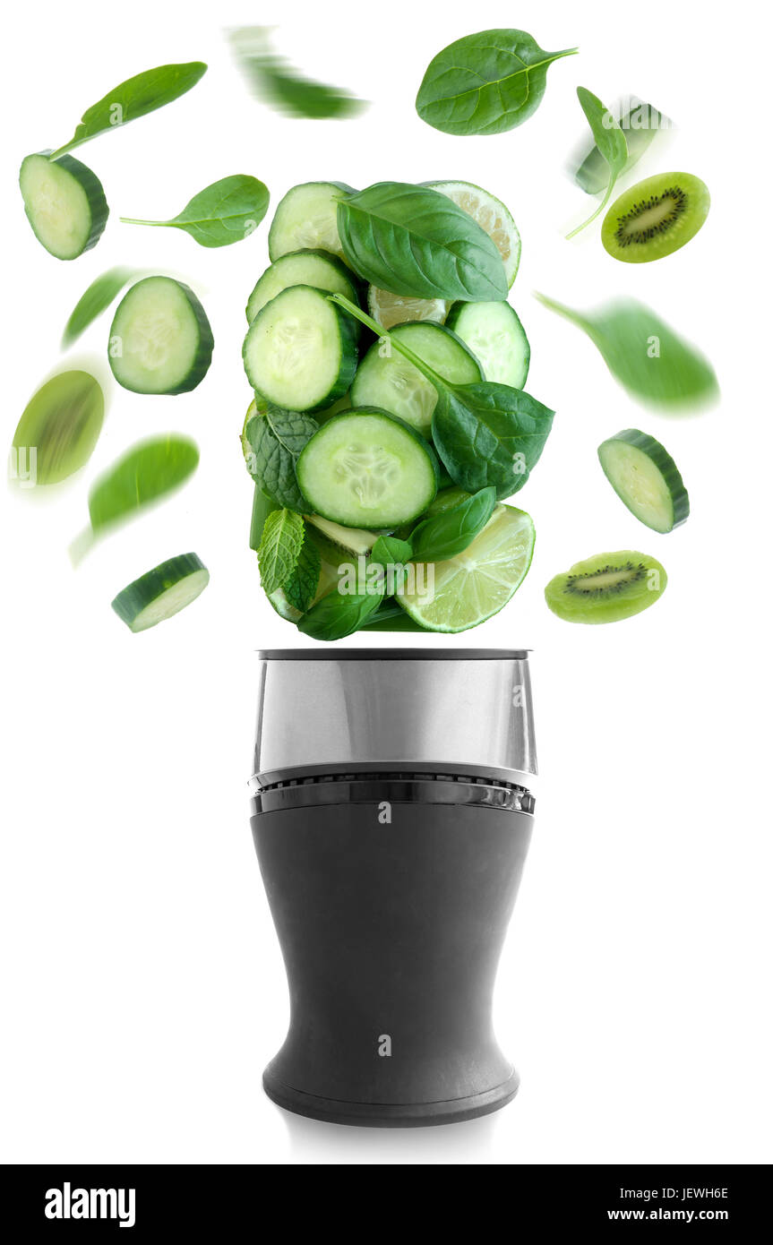 Verde fresco frutta e verdura la filatura al di sopra di un frullatore su sfondo bianco Foto Stock