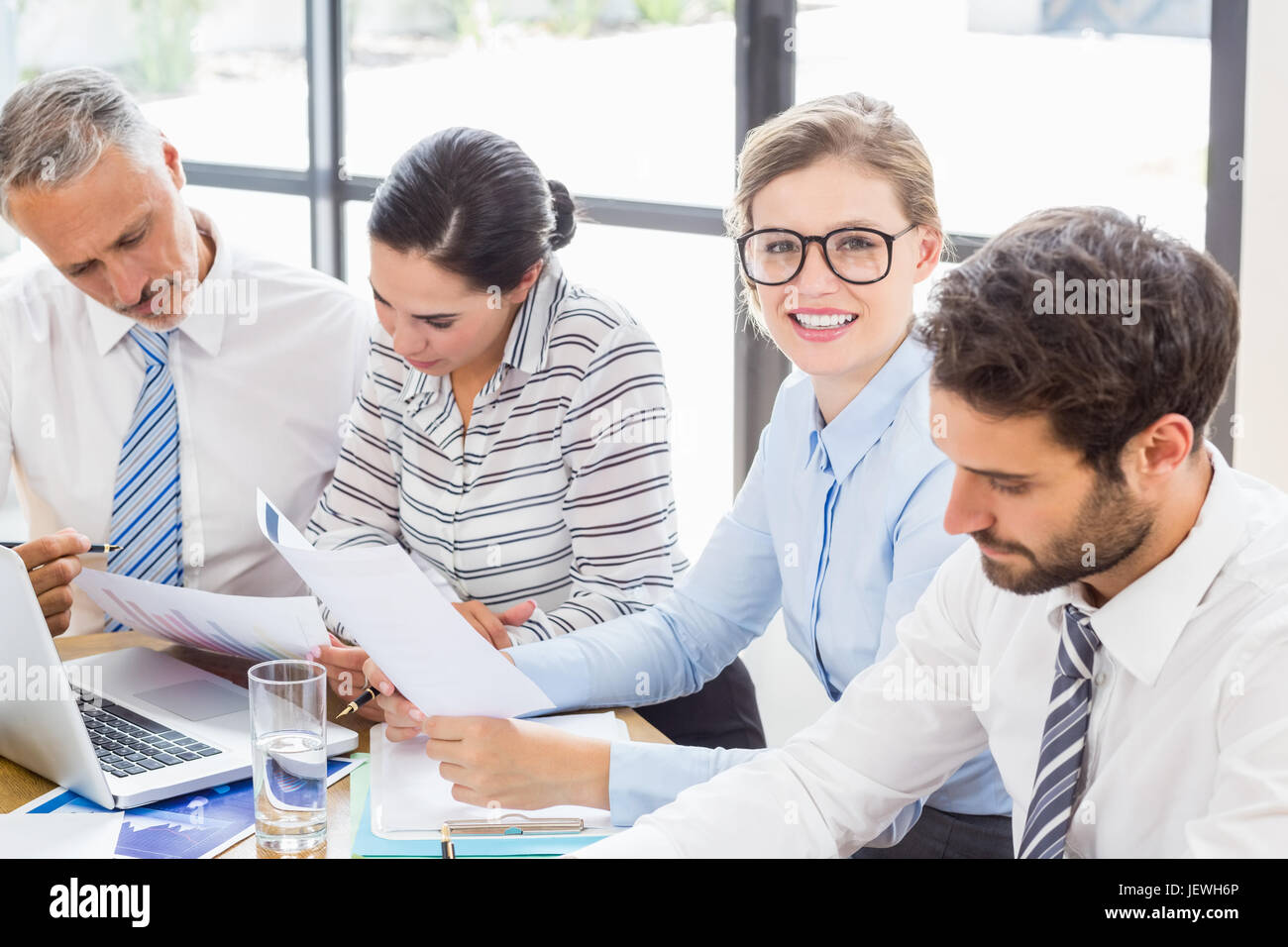 Imprenditrice seduto alla scrivania e sorridente Foto Stock