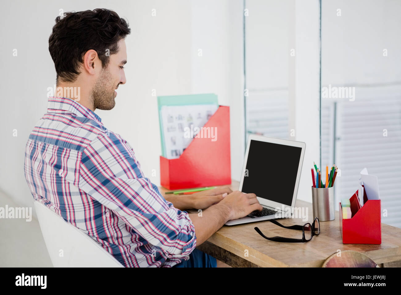 Giovane uomo che lavora alla sua scrivania Foto Stock