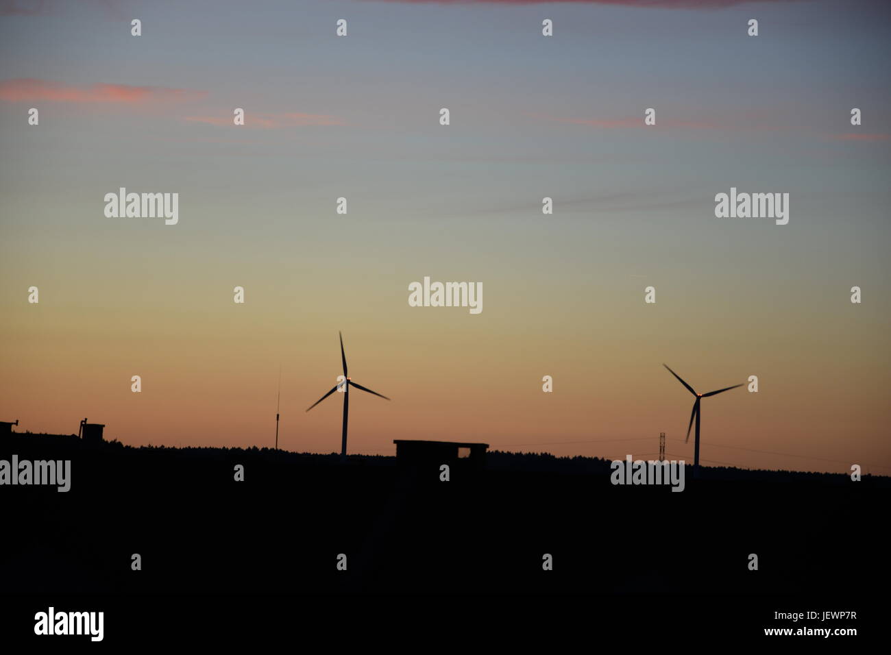 Una vista dalla città sulle sagome tramonto di mulini a vento Foto Stock