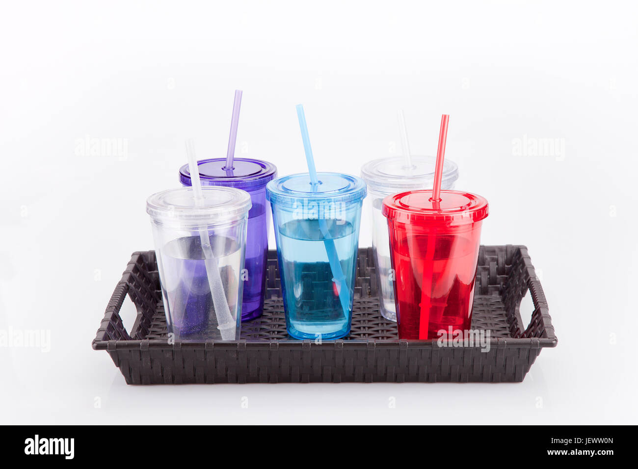 Colorate cilindretto di plastica bicchieri con coperchio e cannuccia in un vassoio di plastica. Tazze di viaggio in un vassoio isolati su sfondo bianco. Foto Stock