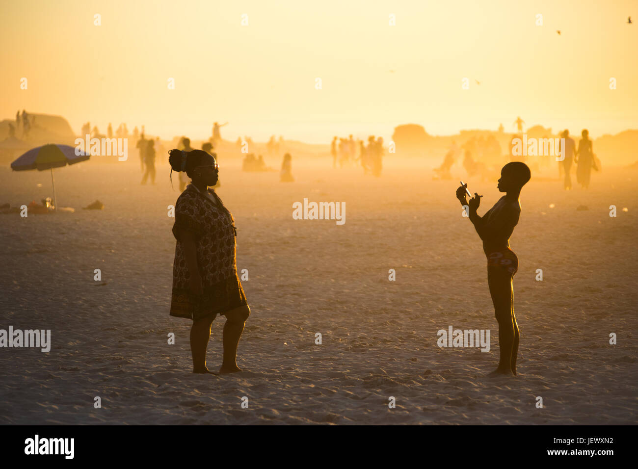 Ragazzo tenendo una donna di foto con uno smartphone sulla spiaggia di Camps Bay, Città del Capo, Sud Africa Foto Stock