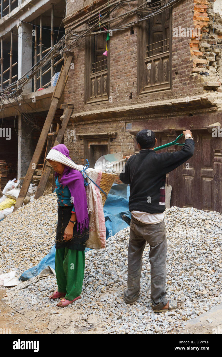 Uomo di ghiaia di caricamento in un cesto portato da una donna, Bhaktapur, Nepal. Foto Stock