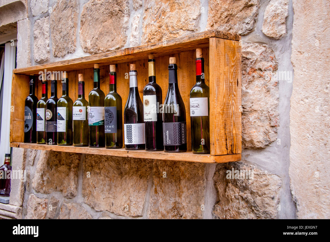 Le bottiglie di vino adornano un muro di pietra nella città di Sudurad, nella splendida isola di Šipan, Croazia Foto Stock