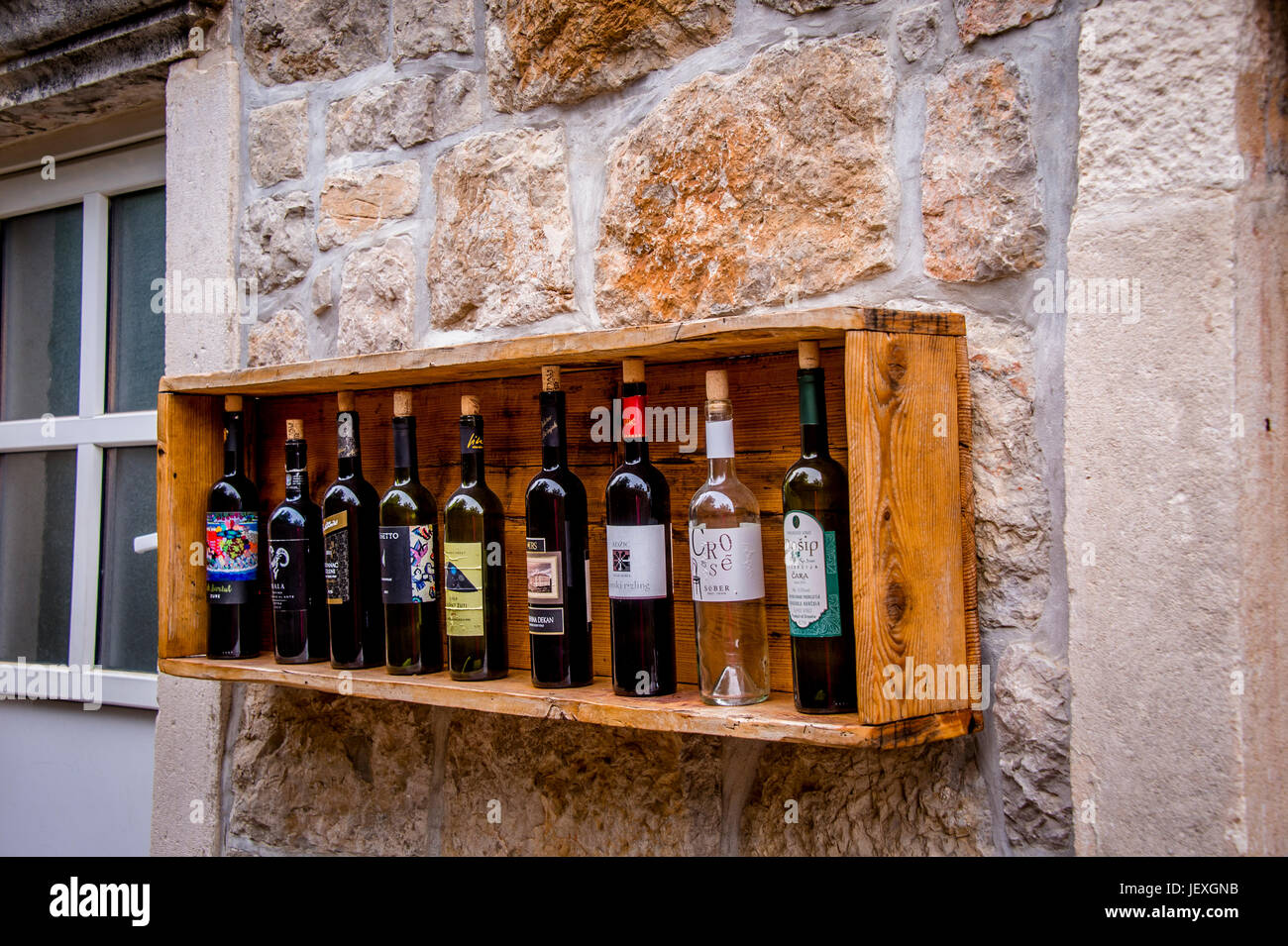 Le bottiglie di vino adornano un muro di pietra nella città di Sudurad, nella splendida isola di Šipan, Croazia Foto Stock