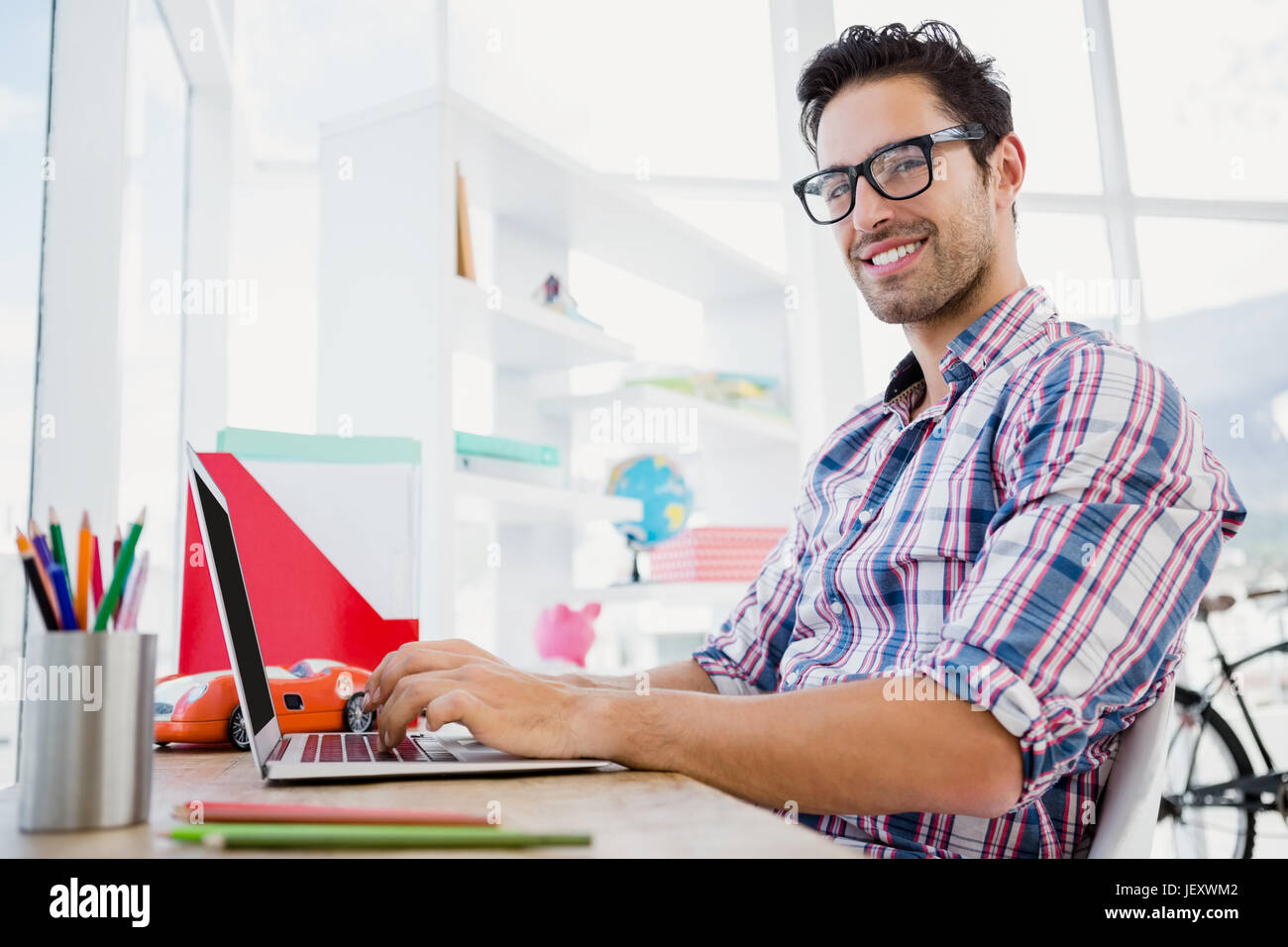 Giovane uomo che lavora alla sua scrivania Foto Stock