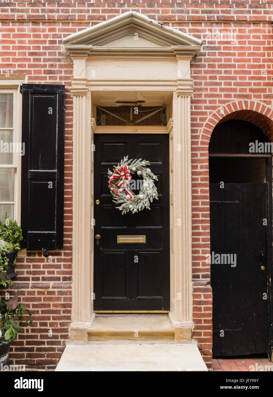 Rosso coloniale porta nel centro storico di Elfreth's Alley in Philadelphia con frontone e ghirlanda di Natale Foto Stock