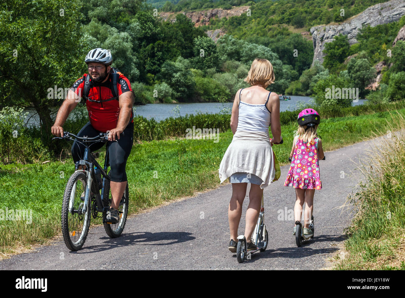 Madre con figlia in scooter e motociclista sulla pista ciclabile nella valle del fiume Berounka, percorso ciclistico europeo della Repubblica Ceca Foto Stock