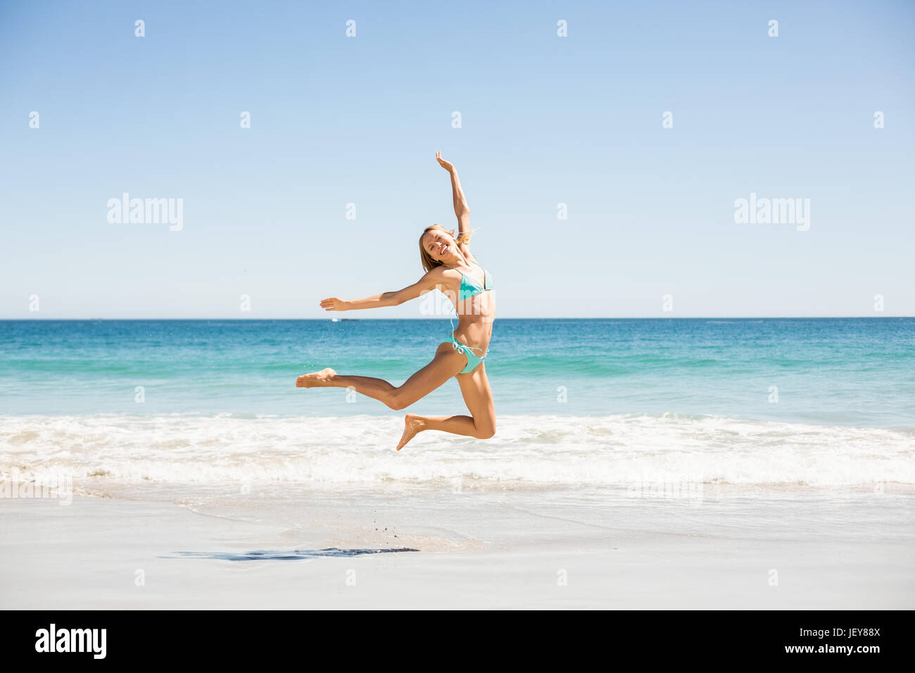 Donna salta sulla spiaggia Foto Stock