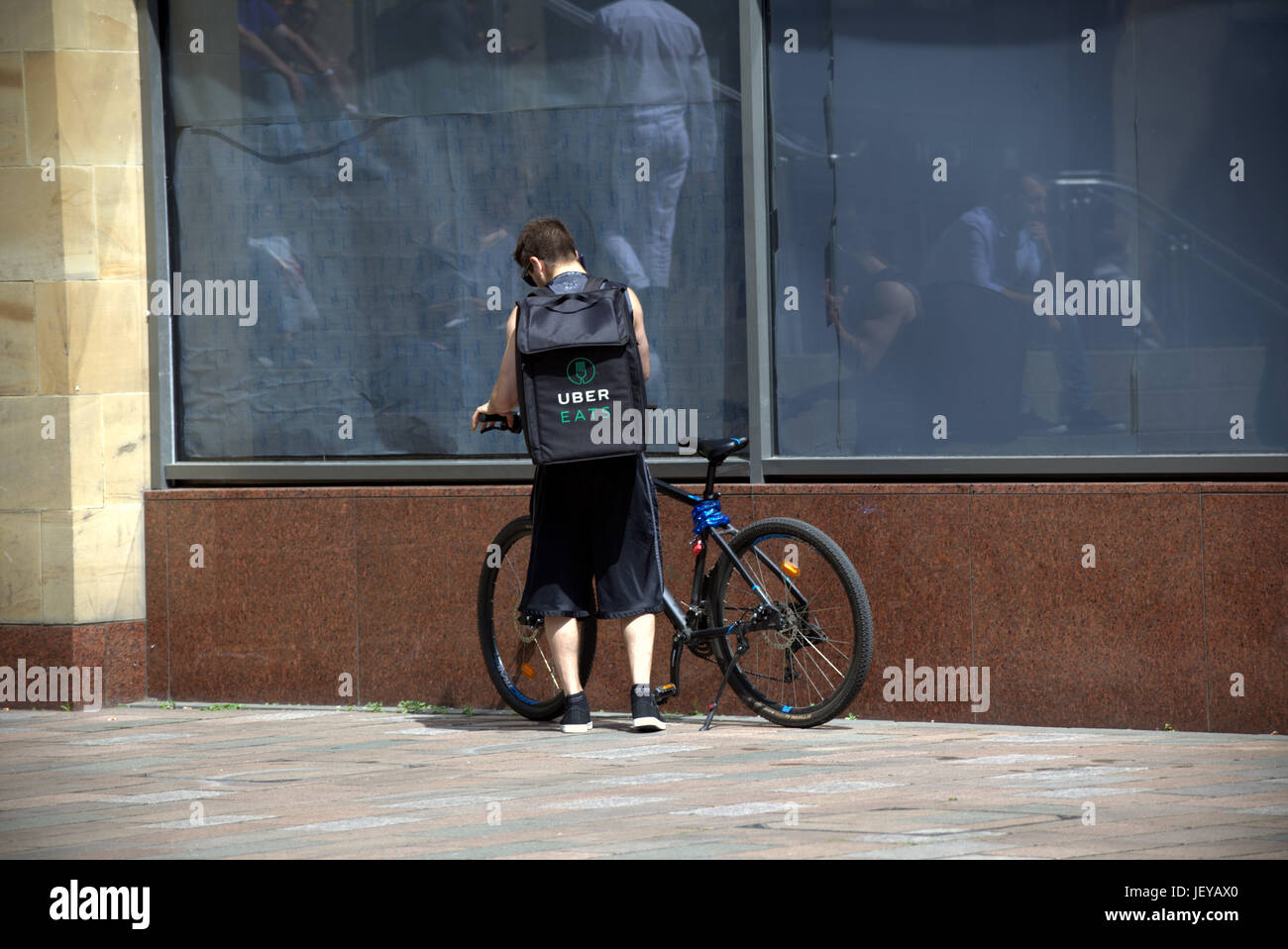 Giovane ragazzo consegna bike ciclista Uber Consegna del cibo bike in attesa per il lavoro Foto Stock