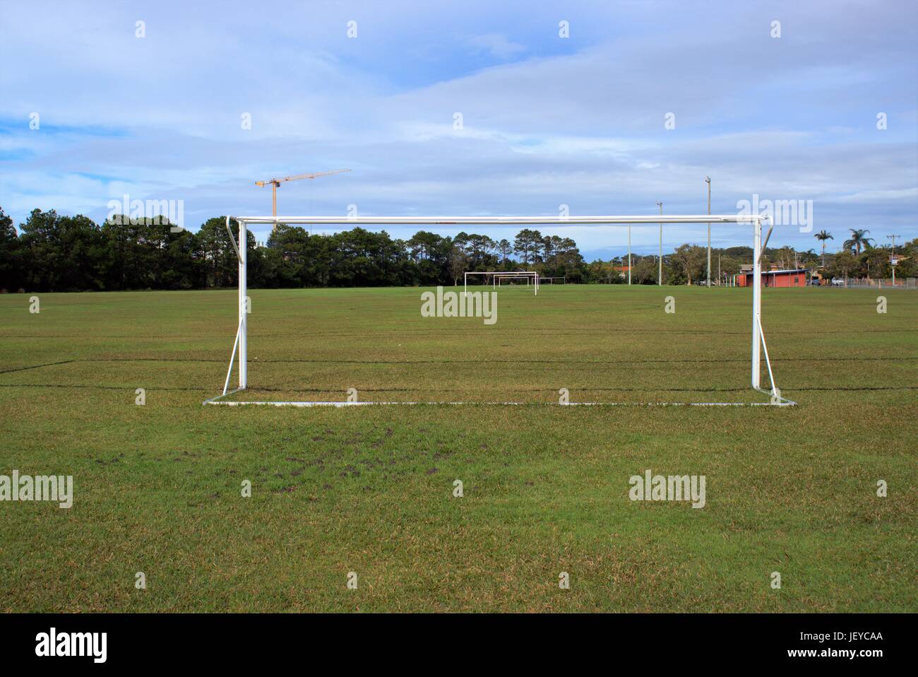 Parco giochi di calcio in Australia. Parco giochi di calcio con pali, proiettori, alberi e una gru in lontananza. Foto Stock