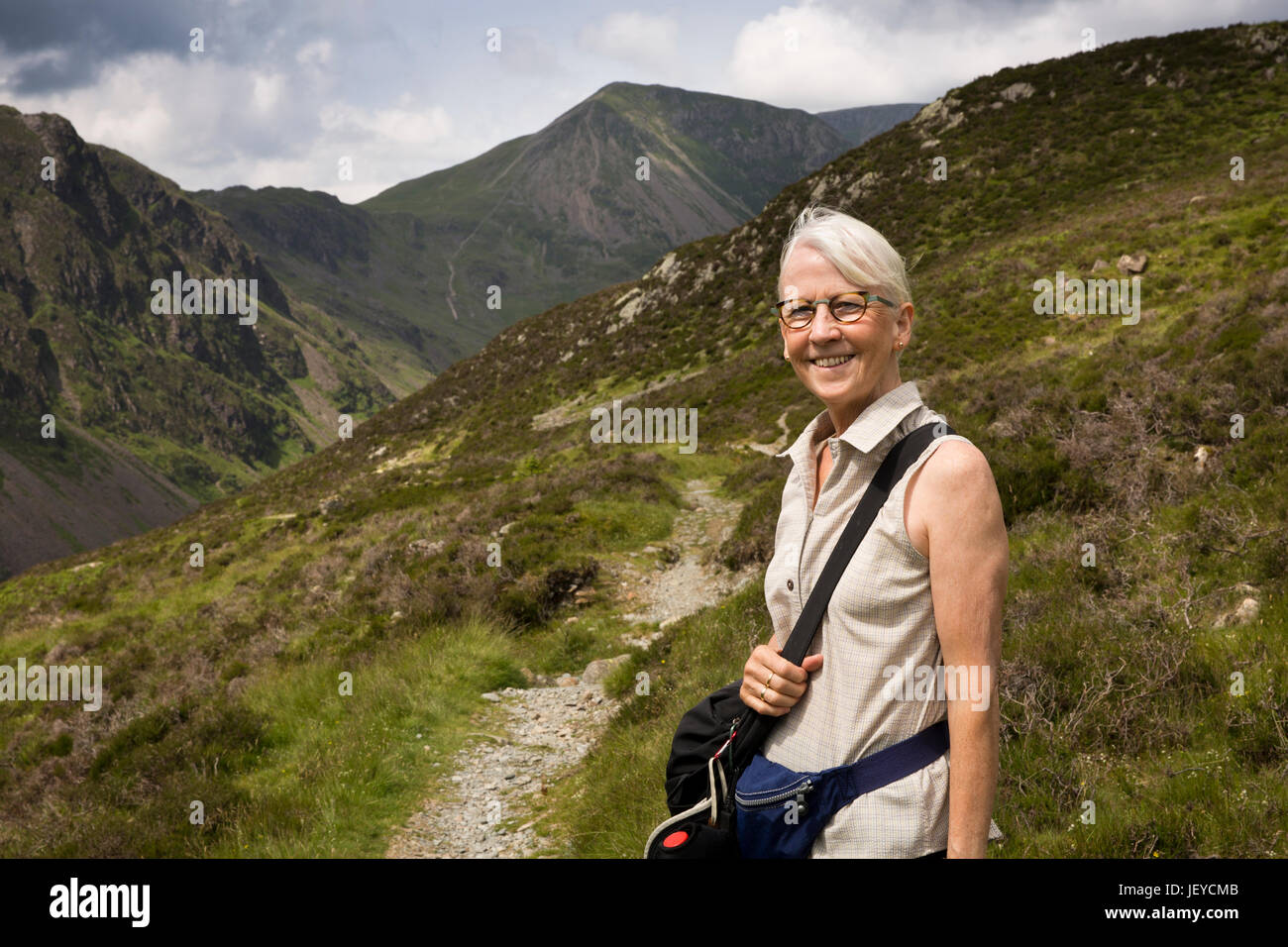 Regno Unito, Cumbria, Fleetwith Pike, femmina senior walker sul percorso passato Buttermere alto stile, accanto Warnscale Beck Foto Stock