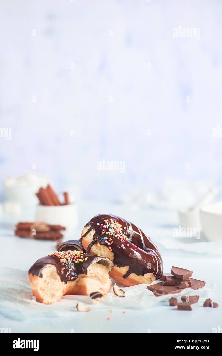 Cioccolato ciambelle vetrata con un pizzico di cannella e su un bianco sullo sfondo di legno Foto Stock