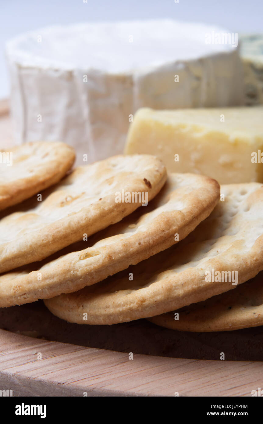 In prossimità di un bordo di cracker con selezione di formaggi in soft focus in background. Profondità di campo. Foto Stock