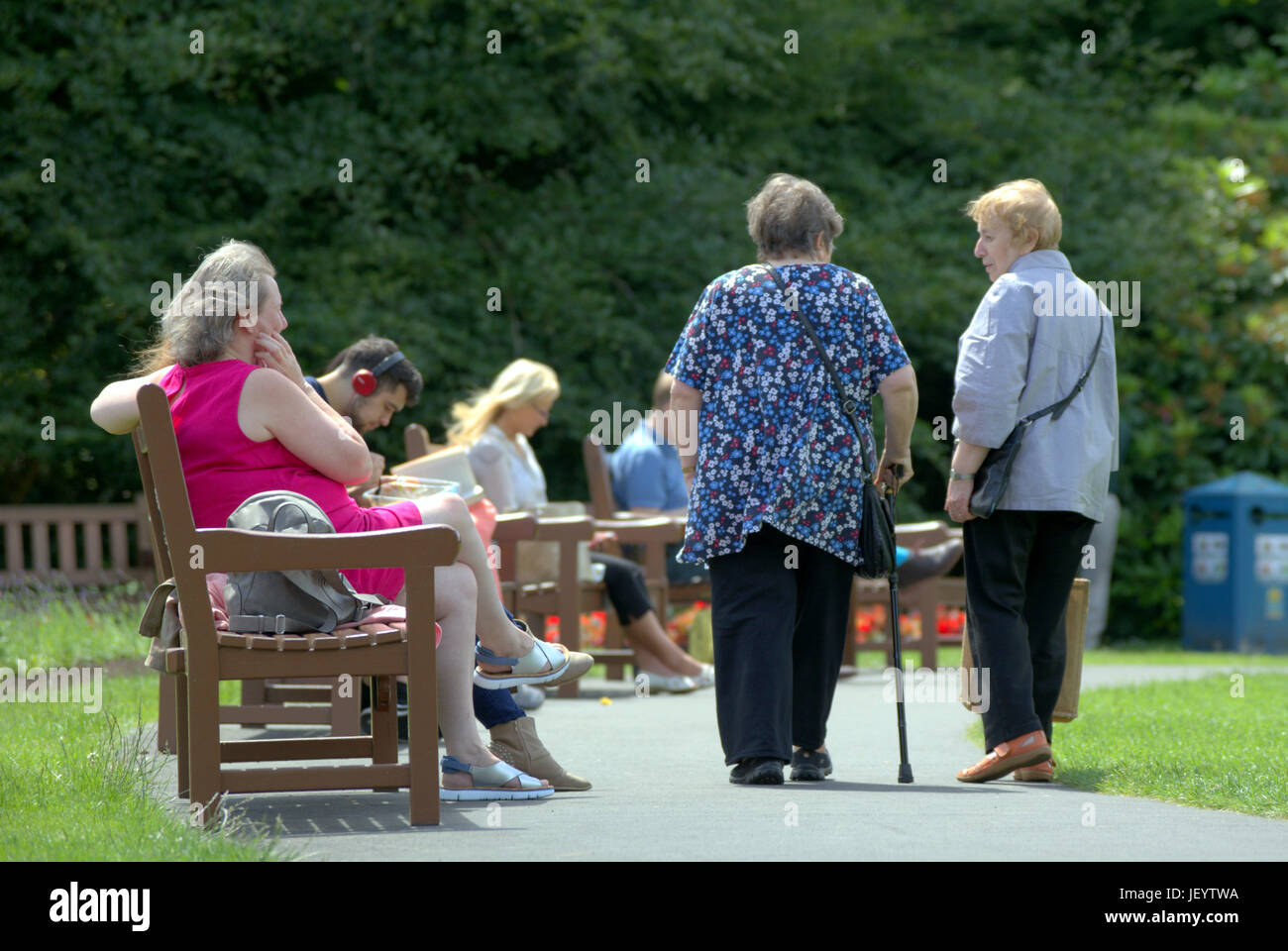 I cittadini anziani o persone anziane anziani a Glasgow Scozia sovrappeso a piedi nel parco con stick o degli aiuti Foto Stock