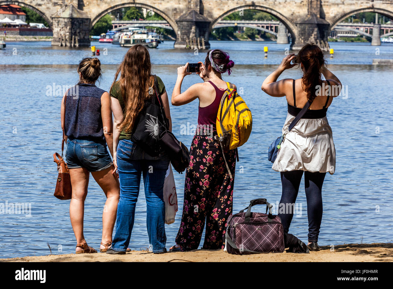 Persone su Strelecky Ostrov che si affacciano sul Ponte Carlo, Praga, Repubblica Ceca backpackers Europa città amici Vista posteriore Foto Stock