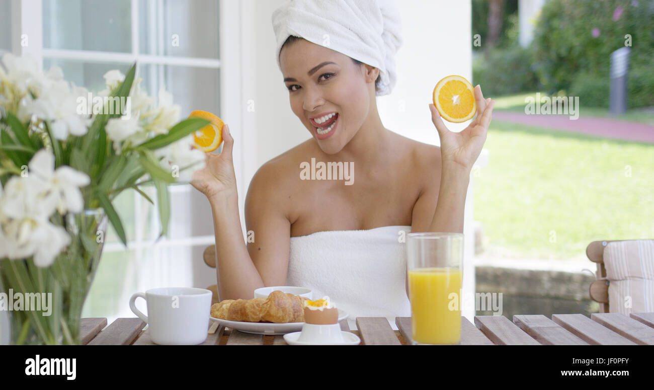 Donna avvolta in asciugamano holding fettine di arancia Foto Stock