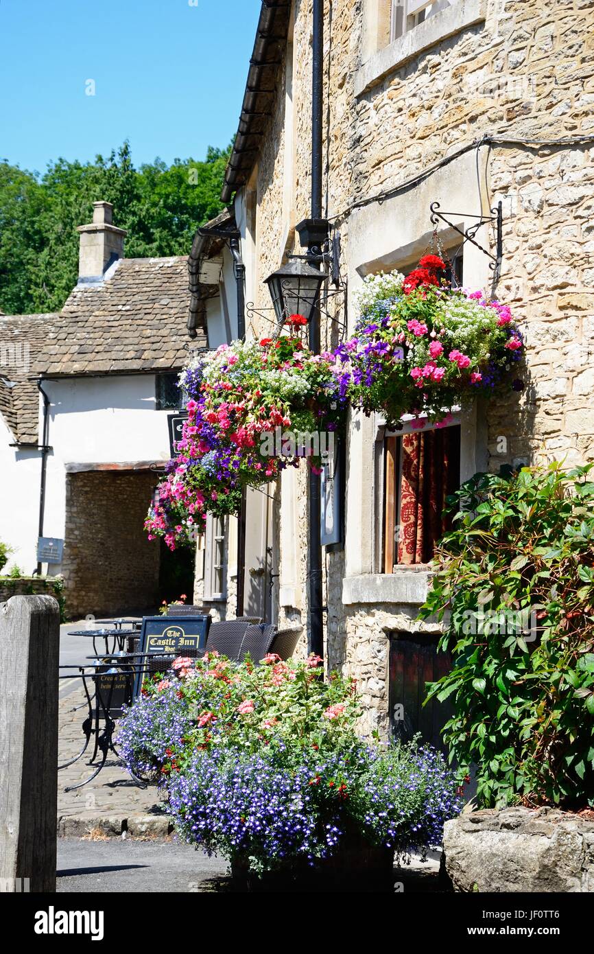 Graziosi fiori al di fuori Il Castle Inn nel centro di villaggio, Castle Combe, Wiltshire, Inghilterra, Regno Unito, Europa occidentale. Foto Stock